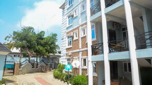 A multi-story residential building with balconies, a gated entrance, and a paved courtyard.