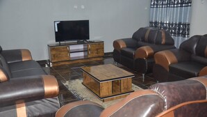 A modern living room with leather sofas, a wooden coffee table, and a flat-screen TV on a wooden cabinet.
