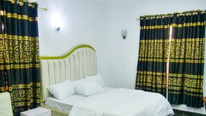 A neatly arranged bedroom with a bed, a bedside table, and curtains.