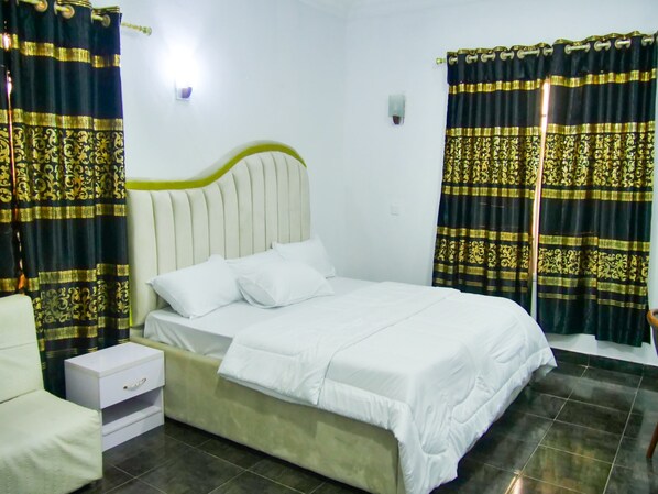 A neatly arranged bedroom with a bed, a bedside table, and curtains.