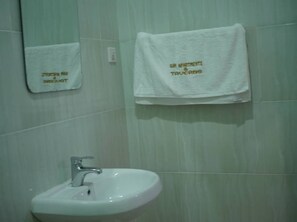 A bathroom with a sink, a towel hanging on the wall, and a mirror reflecting the towel.