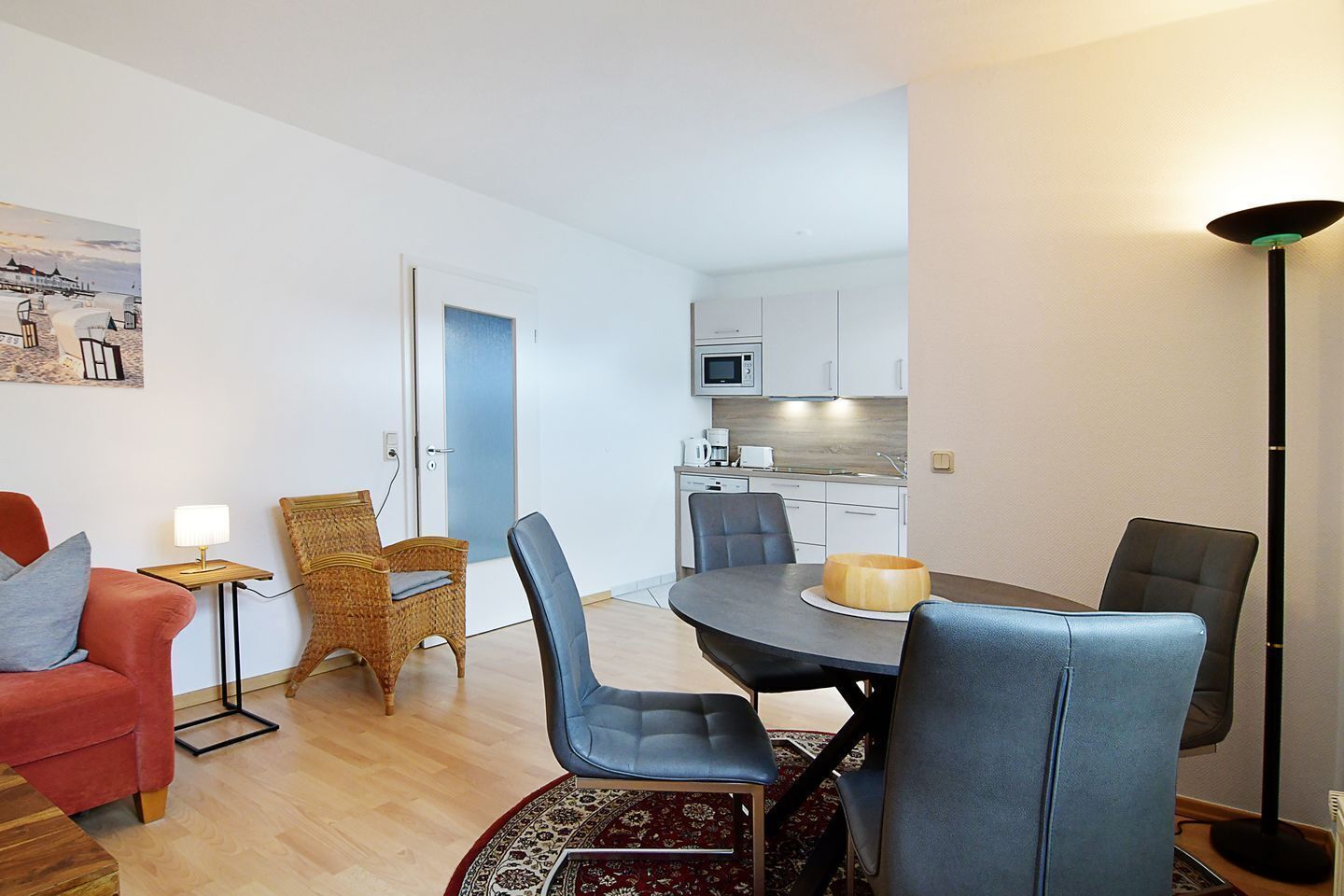 Un espai vital compacte amb zona de menjador, petita cuina i una porta que condueix a una altra habitació.