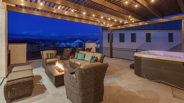 Une terrasse extérieure couverte, aménagée avec des meubles en osier, un foyer et un jacuzzi.