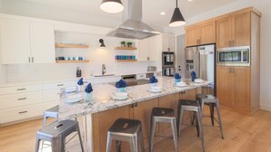 Une cuisine moderne avec des meubles blancs, un plan de travail en granit, des appareils en acier inoxydable et des tabourets de bar.