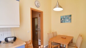 A small kitchen with a radio, a clock, and a dining table with chairs.