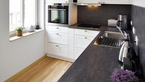 Una cucina moderna con mobili bianchi, un piano di lavoro nero e una finestra con vista.