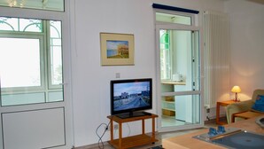A modern living room with a television on a wooden stand, a kitchen area with a sink, and a dining table. - House Wanda Apartment 05 - House Wanda (Heringsdorf)