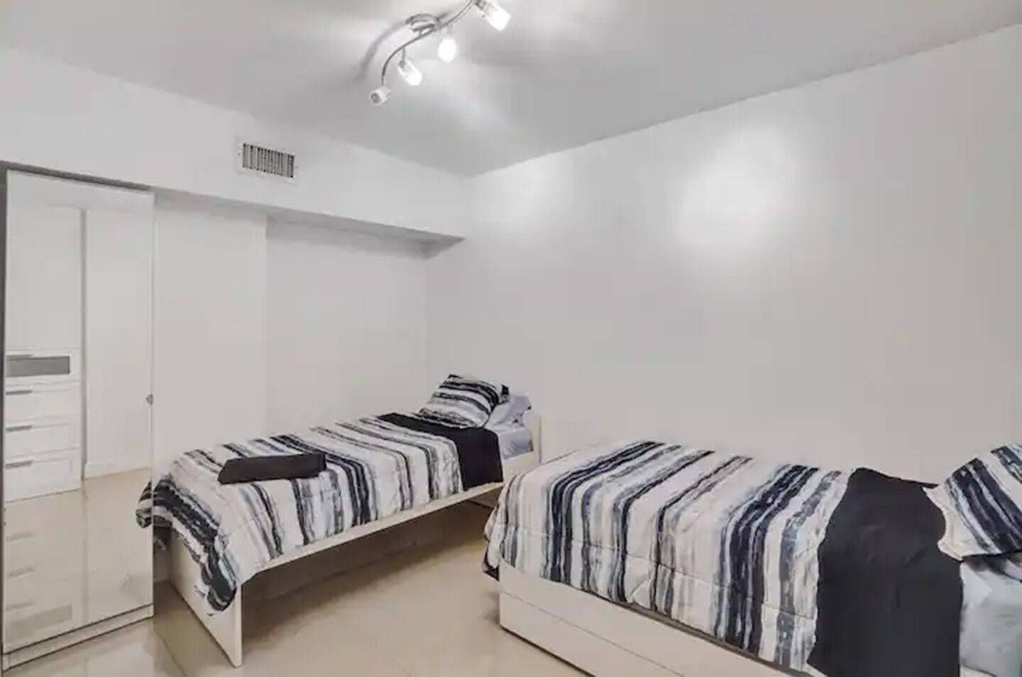 Une chambre avec deux lits simples, une armoire et un luminaire au plafond.
