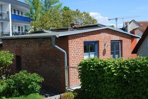 A small brick building with a blue door and window shutters, surrounded by greenery. - Blankenese House - Quaint: Blankenese House on the grounds of Villa Hamburg (Heringsdorf)