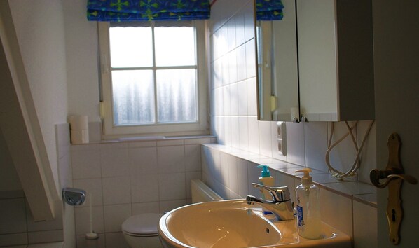 Un bany amb un lavabo, un mirall i una finestra.