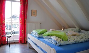 Une chambre à coucher avec un lit, une chaise, un radiateur et une fenêtre avec des rideaux.