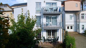 Ein zweistöckiges Gebäude mit Balkon und einer Terrasse mit Gartenmöbeln.