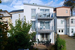Un bâtiment à deux étages doté d’un balcon et d’un patio aménagé avec du mobilier d’extérieur.