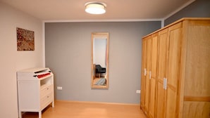Ein Zimmer mit einem Holzschrank, einer weißen Kommode und einem Spiegel an der Wand.
