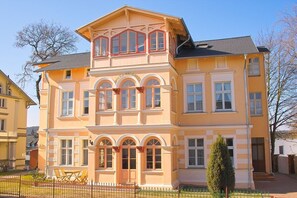 Un immeuble à plusieurs étages, doté d’une façade symétrique, de grandes fenêtres et d’un balcon bien visible.