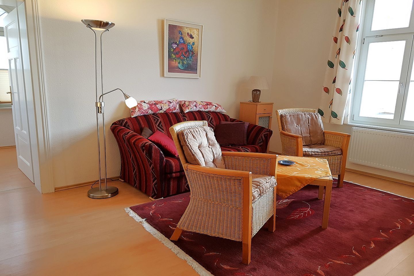 Een woonkamer met een bank, twee fauteuils, een salontafel, een vloerlamp en een schilderij aan de muur.