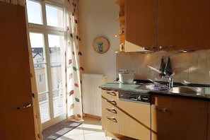 Une cuisine avec une fenêtre, une horloge et un grille-pain sur le plan de travail.
