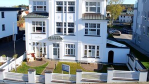 Un edificio blanco de varios pisos con fachada simétrica, ventanas amplias y una entrada central.