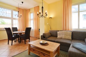 Uma sala de estar aconchegante com um sofá, uma mesa de centro de madeira e um espaço de jantar com cadeiras e uma mesa.
