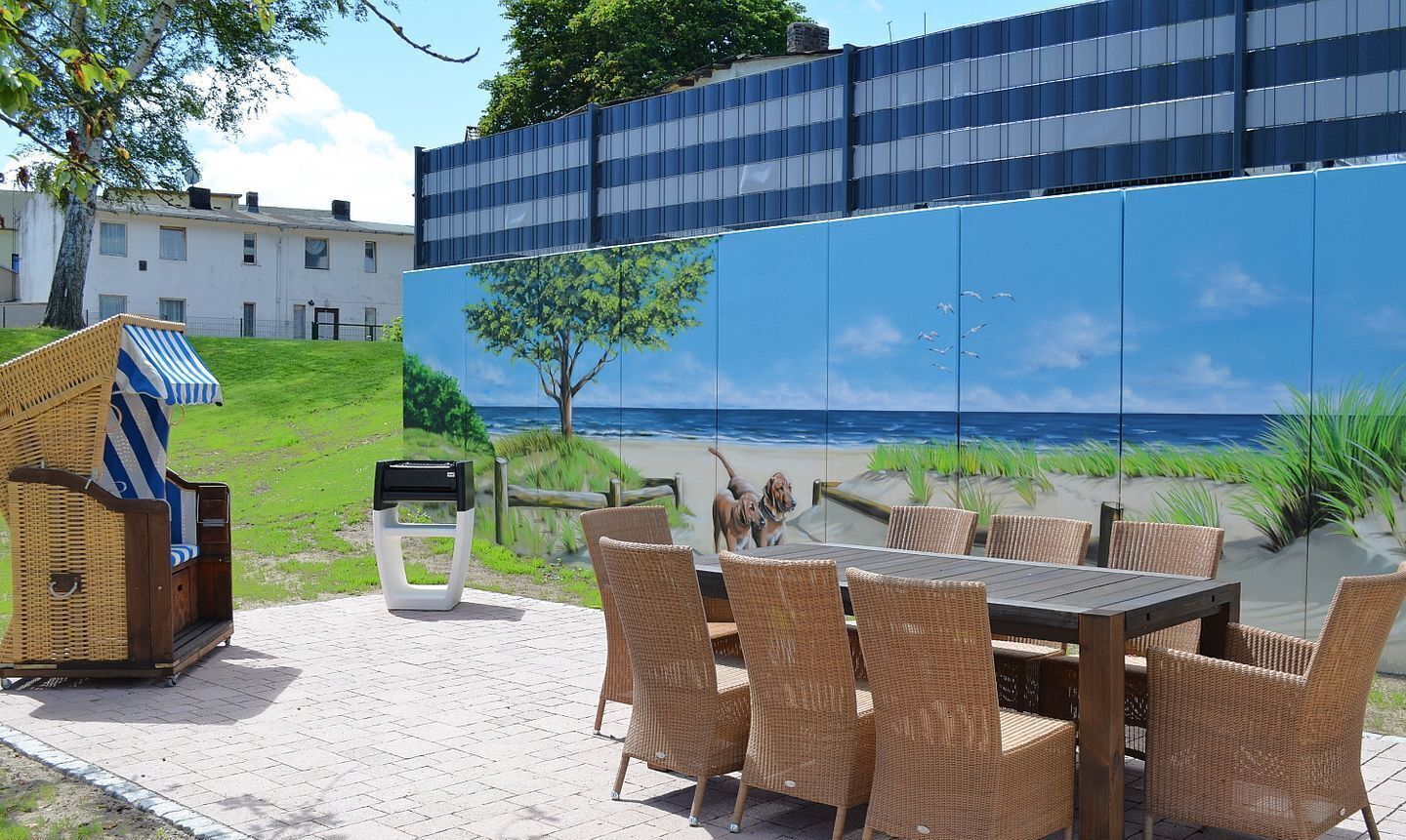 Un espace extérieur aménagé avec des meubles en osier et offrant une vue sur la plage grâce à une grande fenêtre.