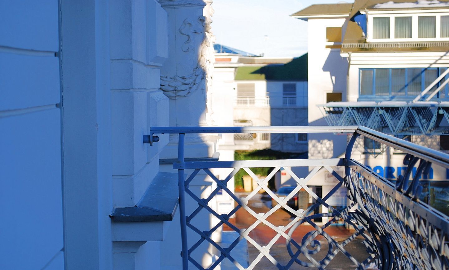 Ein Balkon mit Metallgeländer, der auf eine Straße hinausblickt.