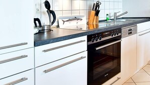 A modern kitchen with white cabinetry, a built-in microwave, a stove, and a sink.