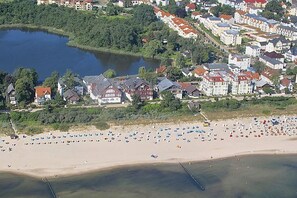 An aerial view of a coastal town with a beach, houses, and a lake.