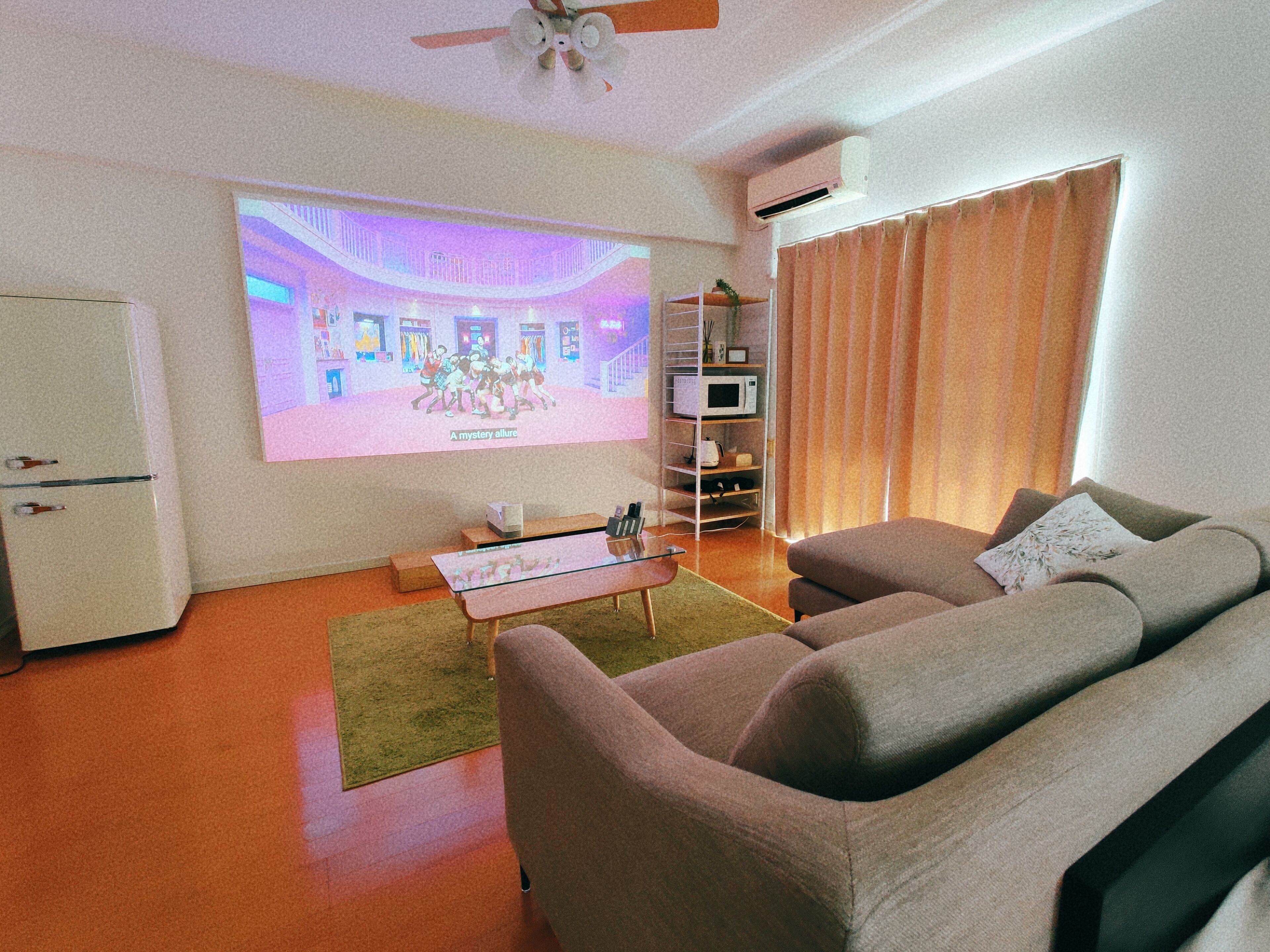 A living room with a flat-screen TV, a sofa, a coffee table, a TV stand, and a bookshelf.