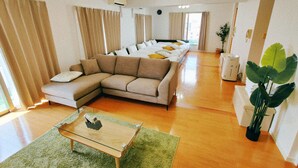 A living room with a sectional sofa, a glass coffee table, and a green rug.