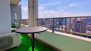 A balcony with a round table, a radiator, and a view of a cityscape.