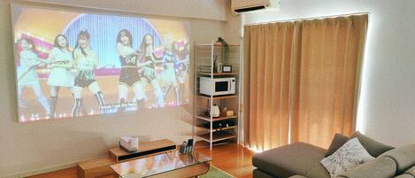A living room with a flat-screen TV, a ceiling fan, a sofa, a coffee table, and a microwave.