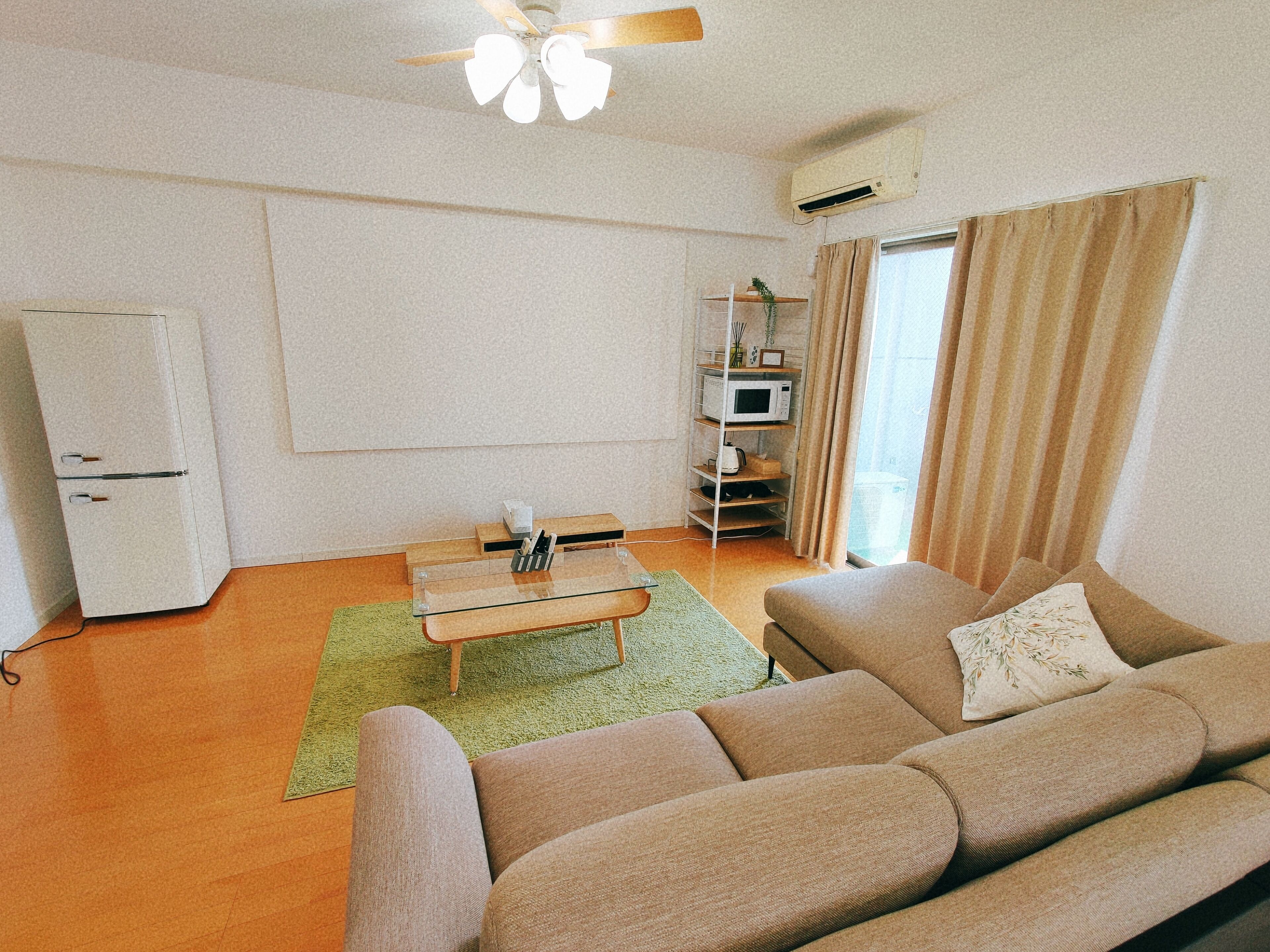 Ein Wohnzimmer mit einer Couch, einem Couchtisch, einem Fernseher, einer Mikrowelle und einem Kühlschrank.