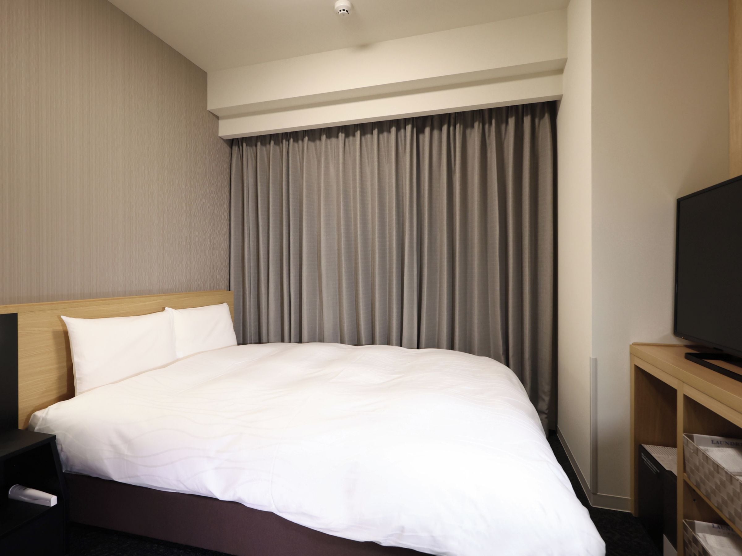 Une chambre d’hôtel avec un grand lit, un téléviseur à écran plat et une table de chevet en bois.