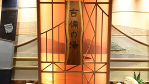 A wooden sign with Japanese characters in a room with a warm, orange-lit background and a geometric wall design. - Dormy Inn Okayama (Okayama)