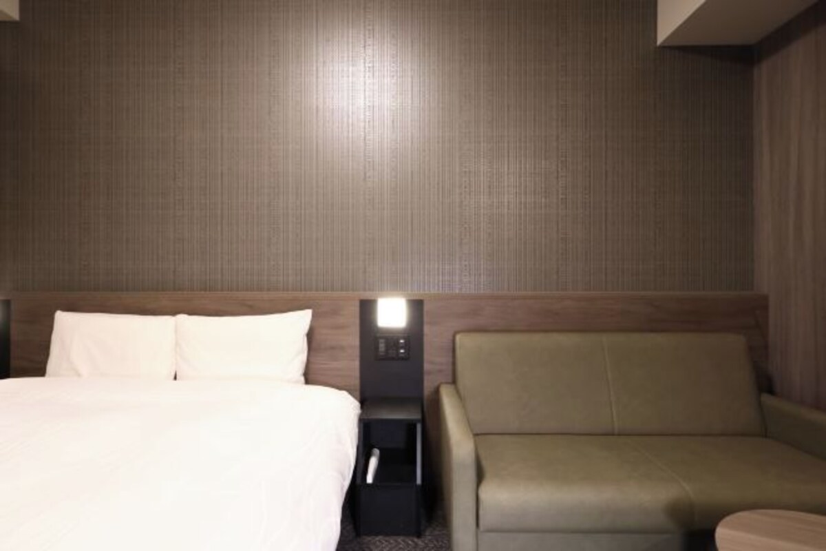 A hotel room with a bed, a nightstand, and a leather armchair.