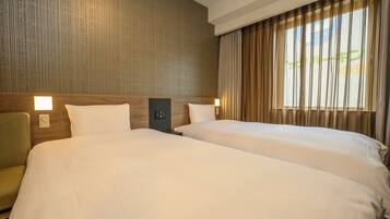 Habitación de hotel con dos camas, cabecera de madera, mesita de noche y ventana con cortinas.