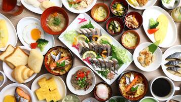A variety of dishes including sushi, sashimi, and other Asian cuisine, arranged on a wooden table.