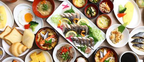 A variety of dishes including sushi, sashimi, and other Asian cuisine, arranged on a wooden table.