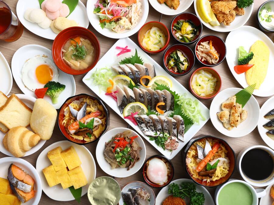 A variety of dishes including sushi, sashimi, and other Asian cuisine, arranged on a wooden table.