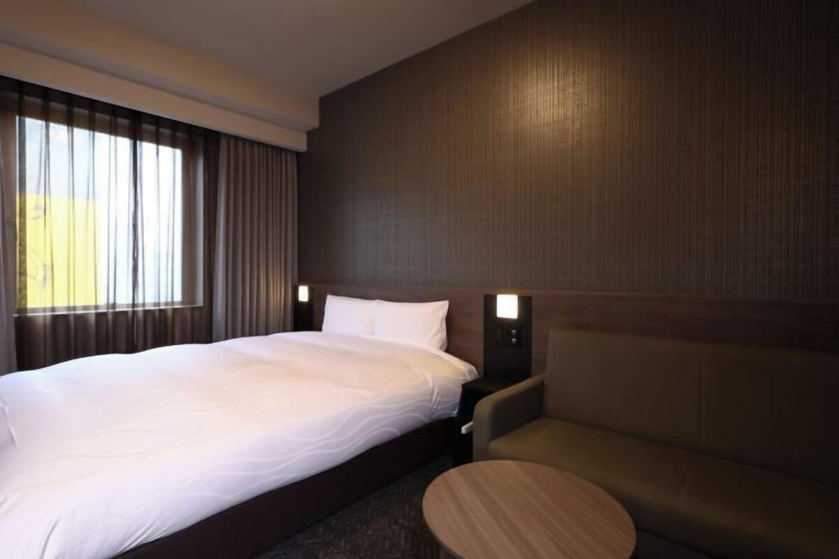 A hotel room with a large bed, a small round table, and a sofa.