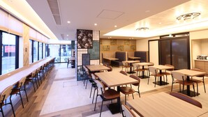 A modern restaurant with long communal tables and booths, large windows, and a clean, contemporary interior design. - Dormy Inn Okayama (Okayama)