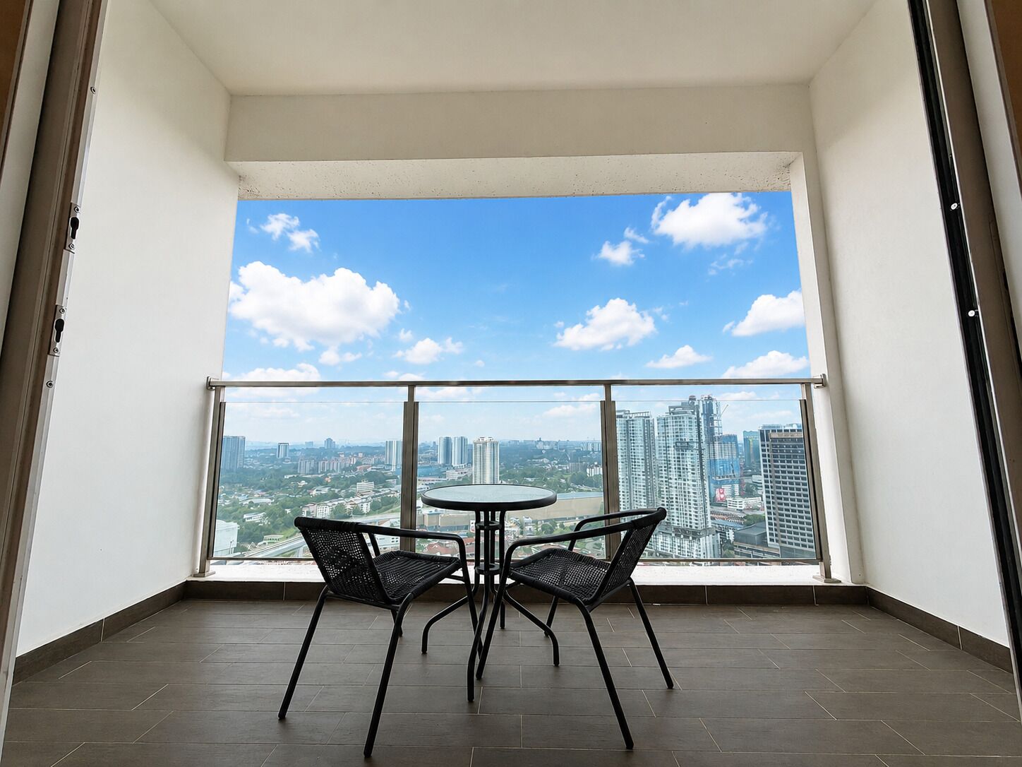 A balcony with a city view, two chairs, and a small round table.