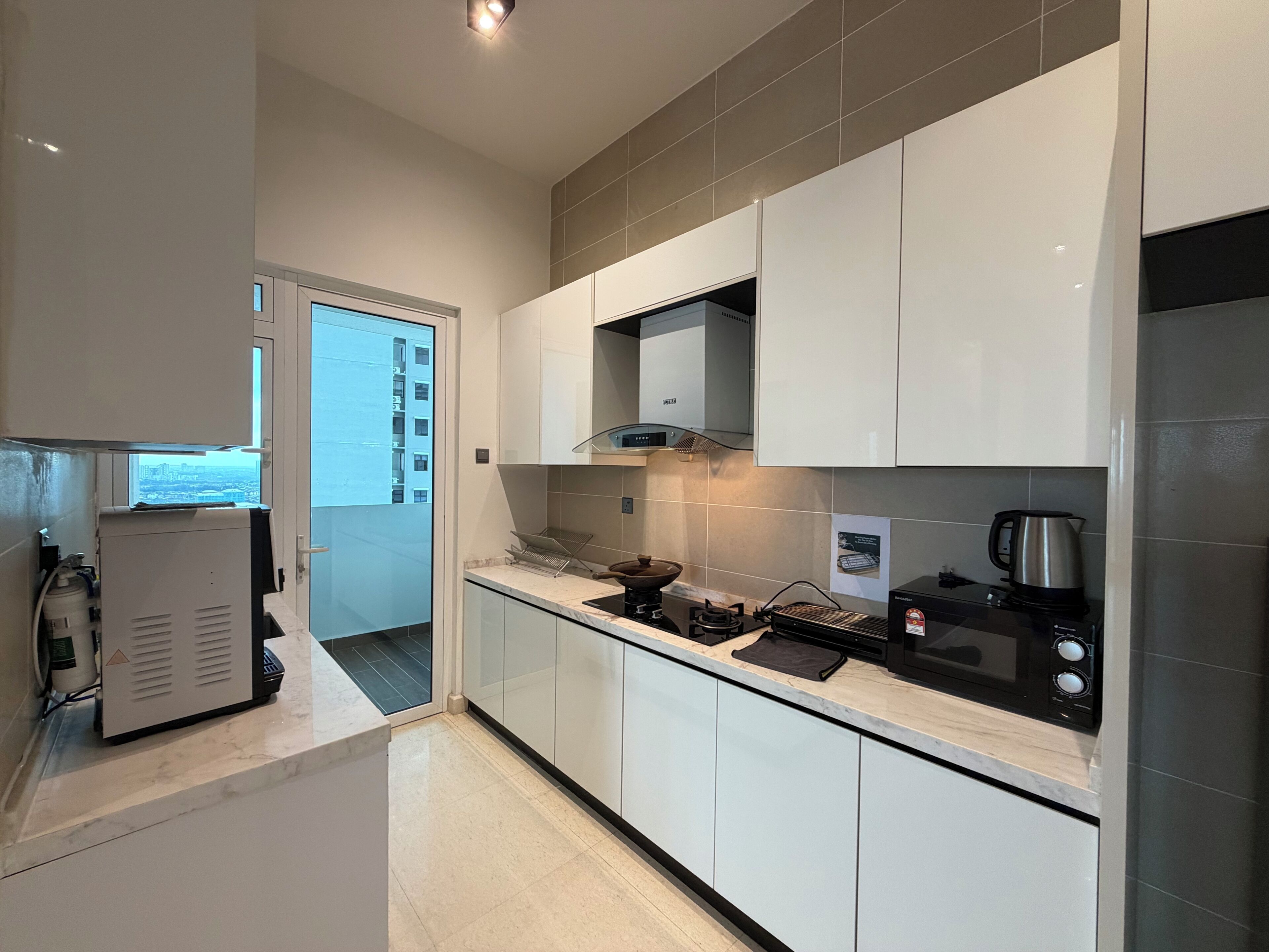 Een moderne keuken met witte kasten, een roestvrijstalen fornuis en een uitzicht op een stadsbeeld door een deur.