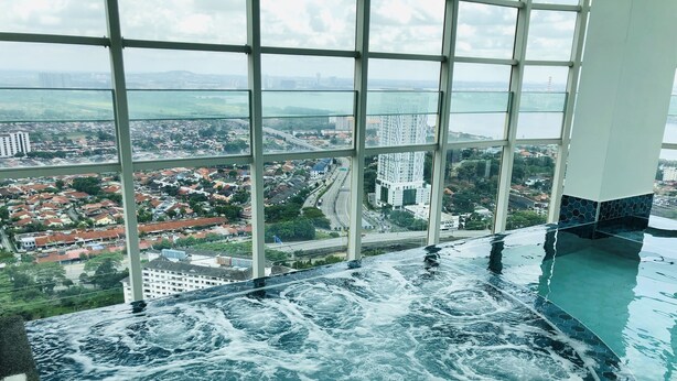 An indoor swimming pool with a view of a cityscape through large windows. - Tri Tower By Antlerzone (Johor Bahru)