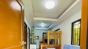 Un corridoio con una cuccetta e un divano, una porta in legno e una lampada a soffitto.