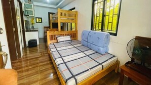 Una stanza con un letto a castello, un divano letto, un tavolino e una ventola.