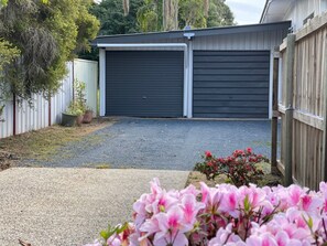 A residential garage with a gravel driveway and a wooden fence.