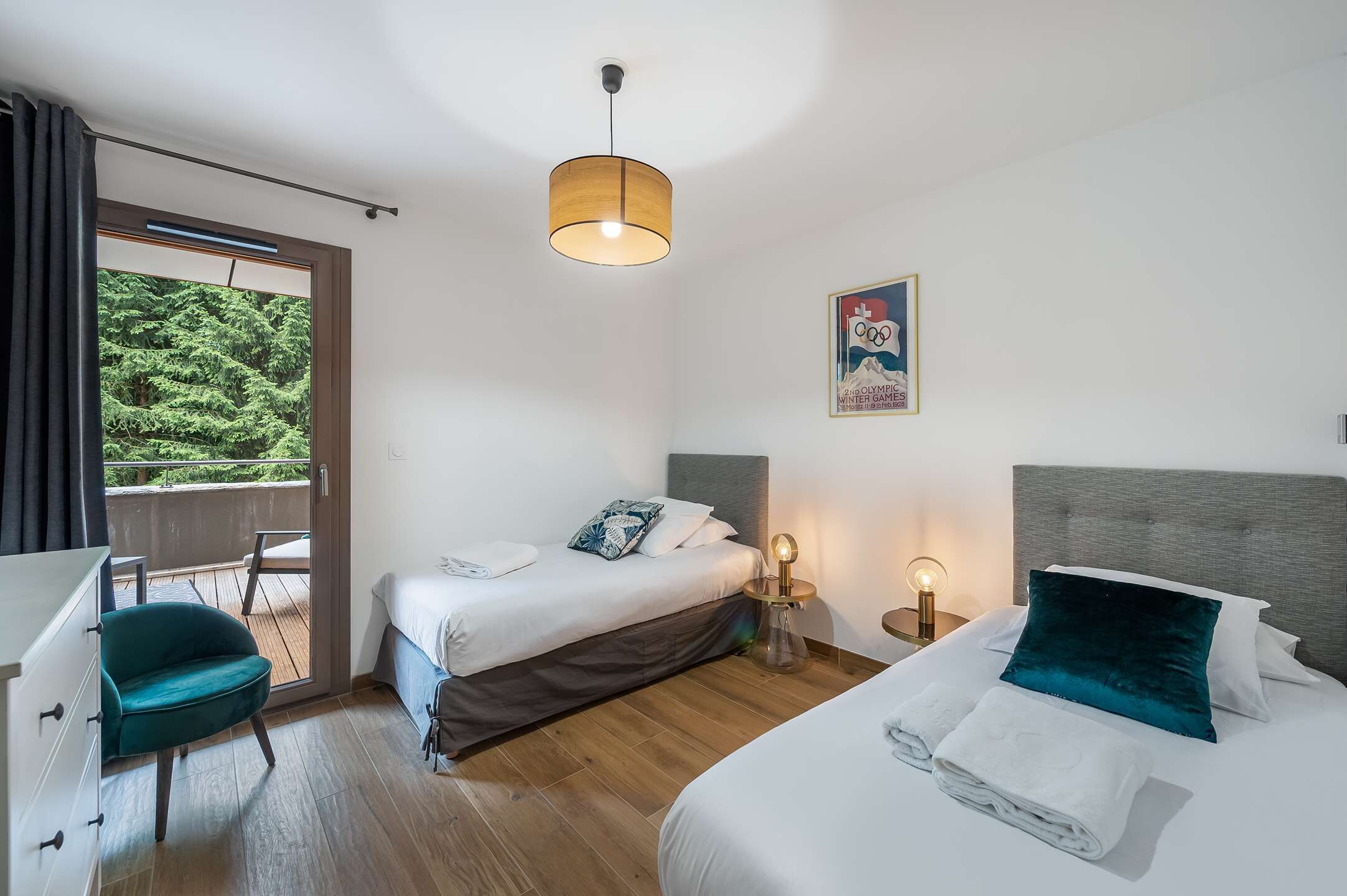 Quarto de hotel com cama, mesa de cabeceira, cadeira e vista para o verde lá fora.