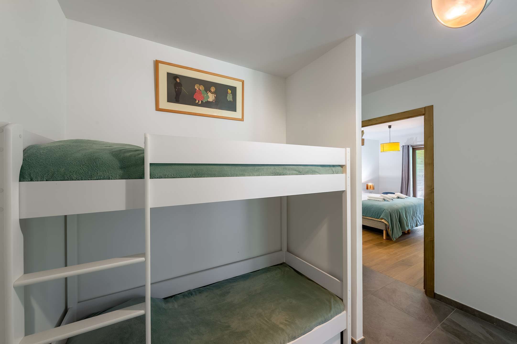 A bunk bed with a green mattress and a framed picture above it.