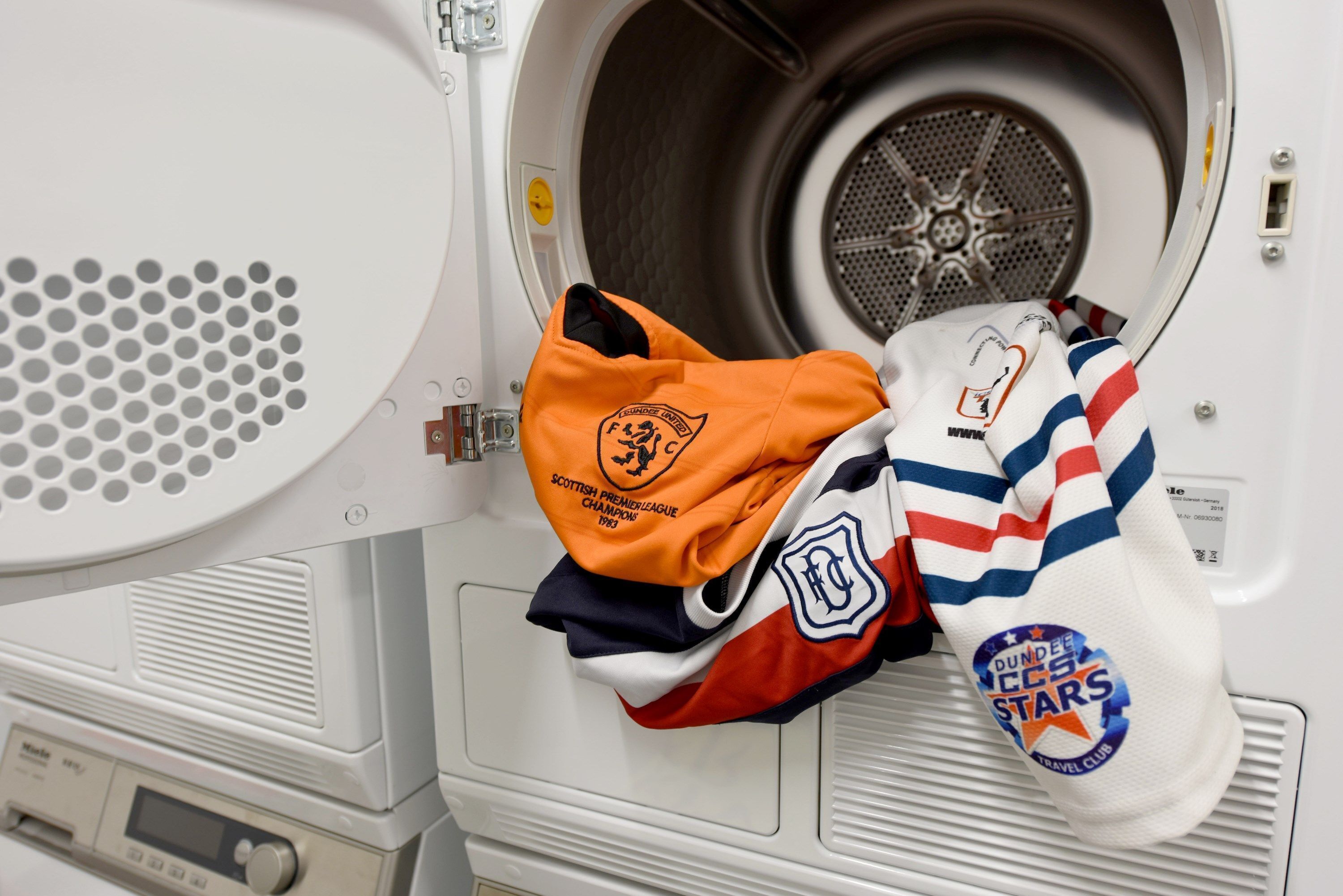 A washing machine with a Scottish Premiership Champions 2018 jersey and a Dundee FC Stars travel club jersey inside.